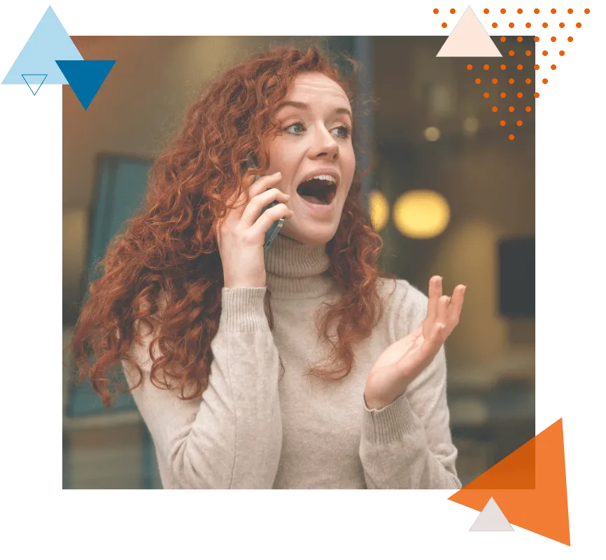 Surprised red-haired woman talking on a smartphone, receiving or sharing big news. The scene represents a tech worker seizing a job opportunity available on Jobshark
